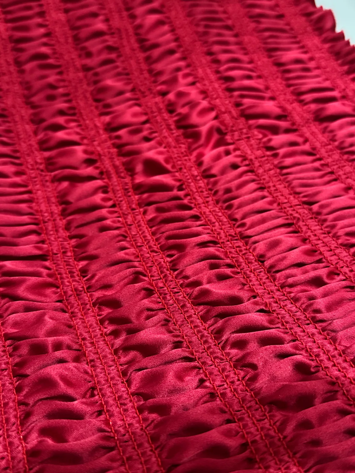 Tela roja satinada con fruncido y puntada con hilo al tono