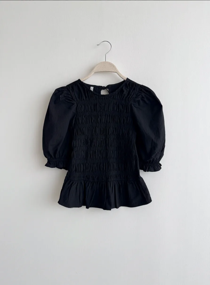 Blusa negra abullonada en percha